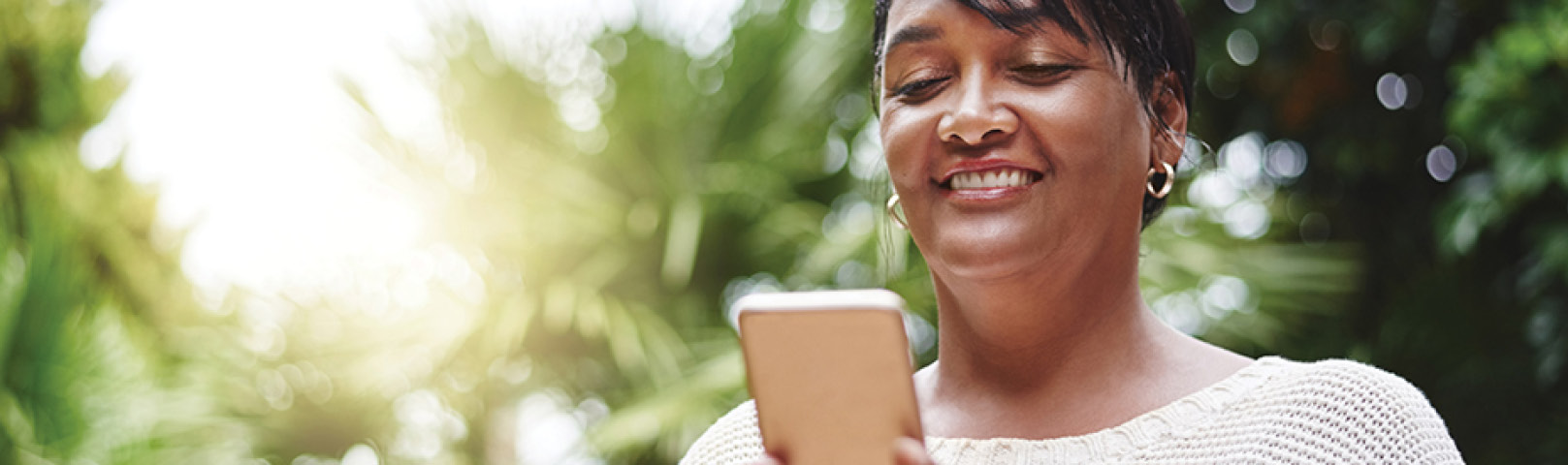 A woman uses apps on her smartphone to help her control her hearing aids and hear better